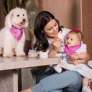 bebê em pé usando bandana babador para bebê vermelha com detalhes preto e branco junto com um gato usando bandana para cachorro e gato vermelho com detalhes branco e preto