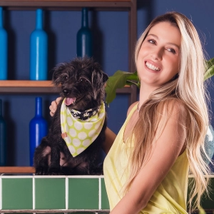 cachorro preto com bandana verde e bolinhas brancas junto com mulher