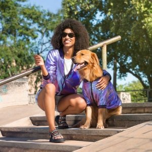 cachorro vestido com jaqueta bomber holográfica para cachorro passeando com uma moça
